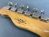 Close-up of vintage Fender Custom Shop guitar headstock with six metal tuning pegs on natural maple wood background