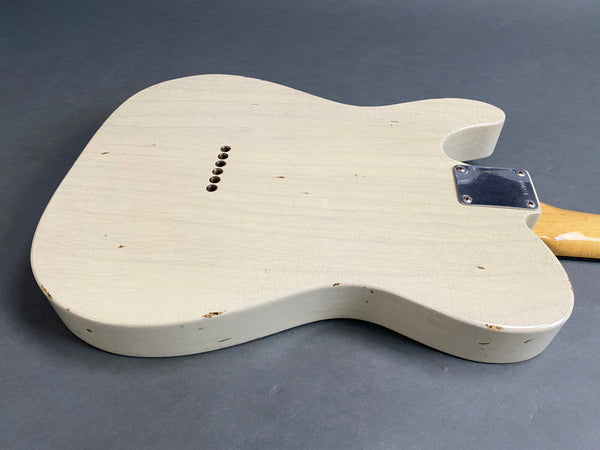 Vintage white distressed solid body electric guitar back with metal neck plate and string ferrules on gray background