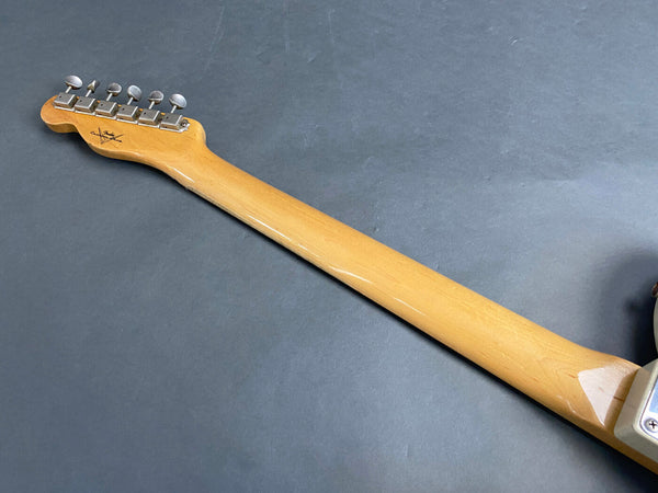 Back of maple guitar neck with tuning pegs and Fender-style headstock on dark gray background