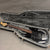 Black electric bass guitar with rosewood fretboard in open hard shell case with gray plush interior liner