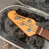 Ernie Ball Music Man StingRay bass guitar headstock with tuning pegs and strings inside gray plush-lined hard case