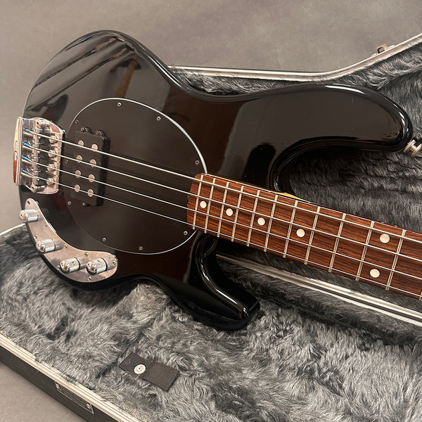 Black electric bass guitar with rosewood fretboard and chrome hardware in a gray plush-lined hard case