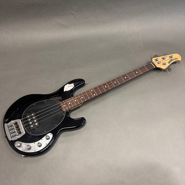 Black electric bass guitar with rosewood fretboard and maple headstock featuring four tuning pegs, chrome bridge, and control knobs on a gray background