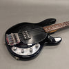 Black electric bass guitar with chrome control knobs and brown fretboard on gray background