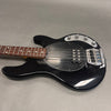 Black electric bass guitar with four strings and chrome hardware on gray surface