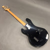Black electric bass guitar with maple neck and chrome tuning pegs, rear view on gray background