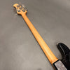 Maple neck and headstock of black electric bass guitar with chrome tuning pegs and metal neck plate against gray background