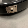 Close-up of black electric guitar output jack plate with four screws on gray surface background