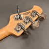 Close-up of maple wood guitar headstock with four metal tuning pegs and "Made in San Luis Obispo California USA" stamp on gray background