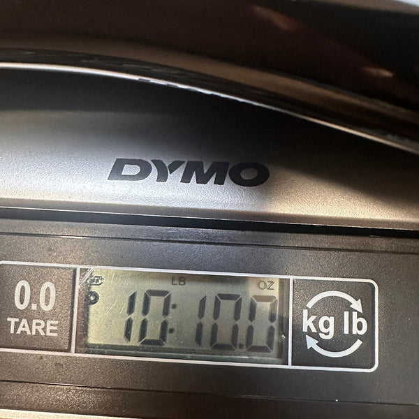 Close-up of DYMO digital scale showing guitar weight as 10 pounds 10 ounces for Coffee House Guitars product listing.