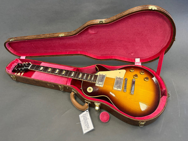 Electric guitar with sunburst finish in open brown and pink velvet lined hard case on gray surface