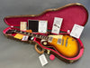 Gibson Les Paul electric guitar with sunburst finish in open brown hard shell case with red velvet interior, including Gibson Gold Warranty, certificate of authenticity, and invoice documents.