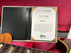 Gibson Custom Certificate of Authenticity for Murphy Lab Ultra Light Aging guitar with serial number 81123 inside red guitar case with partially visible guitar neck and vintage guitar strings packaging