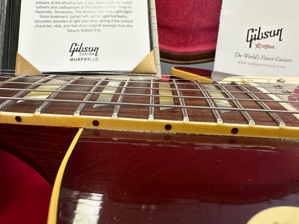 Close-up image of Gibson Custom Murphy Lab guitar fretboard and body with detailed aging finish and Gibson Custom product information cards in the background.