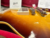 Close-up detail of Gibson custom Murphy Lab Les Paul Standard guitar in light aged bourbon burst finish showing pickups, strings, and bridge in red velvet guitar case with Gibson certification and order sheet