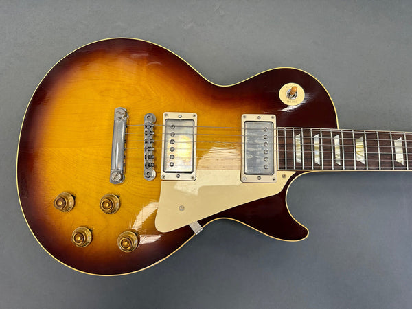 Sunburst electric guitar with dual humbucker pickups and four gold control knobs on a gray background