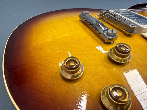 Close-up of sunburst finish electric guitar body showing gold speed control knobs and chrome bridge hardware