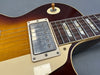Close-up of vintage sunburst electric guitar body showing humbucker pickup, toggle switch, and rosewood fretboard with block inlays