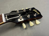 Close up of Gibson Les Paul electric guitar black headstock with tuners and strings on gray background