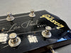 Close-up of Gibson Les Paul electric guitar headstock with tuning pegs and strings on black finish