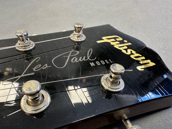 Close-up of Gibson Les Paul electric guitar headstock with tuning pegs and strings on black finish