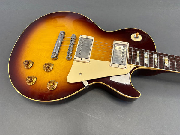 Electric guitar with sunburst finish, cream pickguard, dual humbucker pickups, and four gold control knobs on gray background.