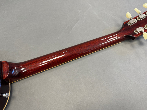 Glossy dark brown wooden guitar neck and headstock with vintage-style tuning pegs on grey background