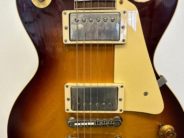 Close-up view of vintage sunburst electric guitar body with dual humbucker pickups, cream pickguard, and chrome bridge hardware