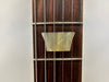 Close-up of guitar fretboard showing trapezoid mother-of-pearl inlay and steel strings on rosewood fingerboard