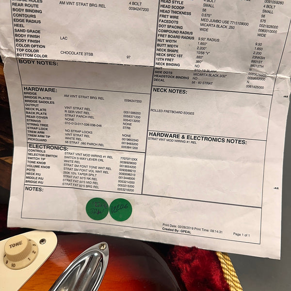 Fender Stratocaster guitar specification sheet with detailed hardware and electronics components list, including AM Vint Strat bridge, vintage Strat neck plate, white pickguard, Strat vintage mod wiring, and tone control settings, displayed on a sunburst guitar body with tone knob and chrome pickup cover visible.