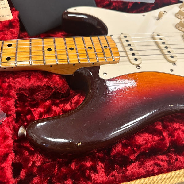 Close-up of vintage sunburst electric guitar body and maple neck with aged finish on red plush guitar case lining