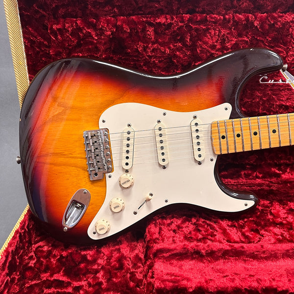 Vintage sunburst electric guitar with three single-coil pickups and maple neck in red velvet-lined case