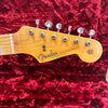 Close-up of Fender Stratocaster guitar headstock with six tuning pegs on red plush background