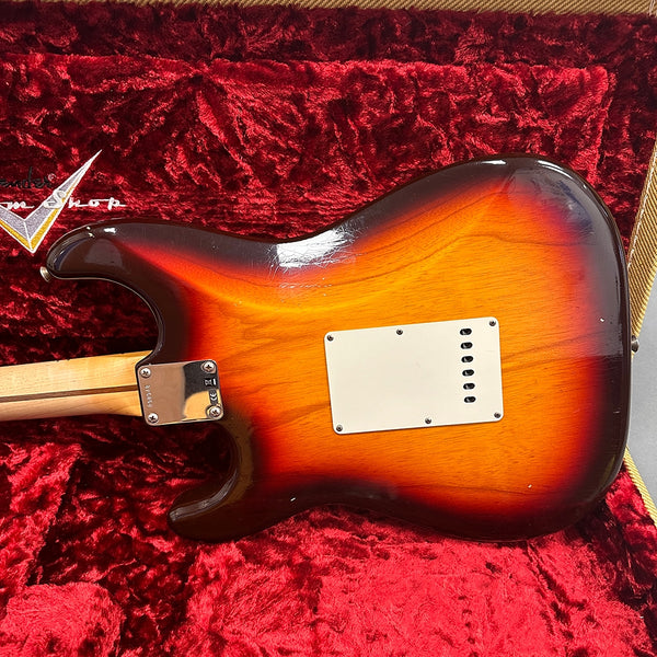 Back of sunburst Fender Stratocaster electric guitar with cream tremolo cavity cover on red plush Fender guitar case interior