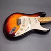 Sunburst electric guitar with white pickguard and maple neck on gray background