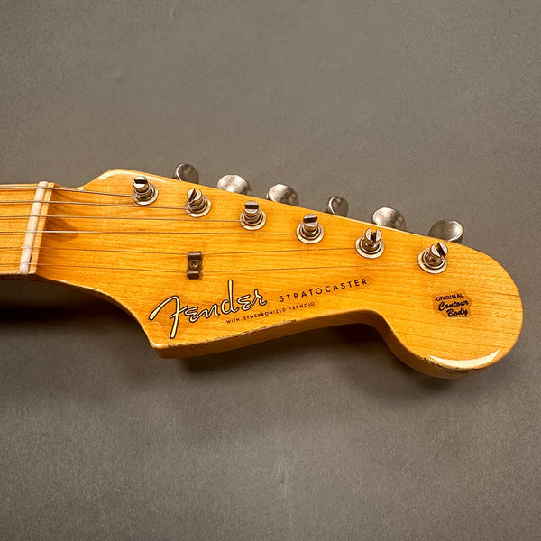 Close-up of Fender Stratocaster guitar headstock with tuning pegs and original contour body logo on a gray background
