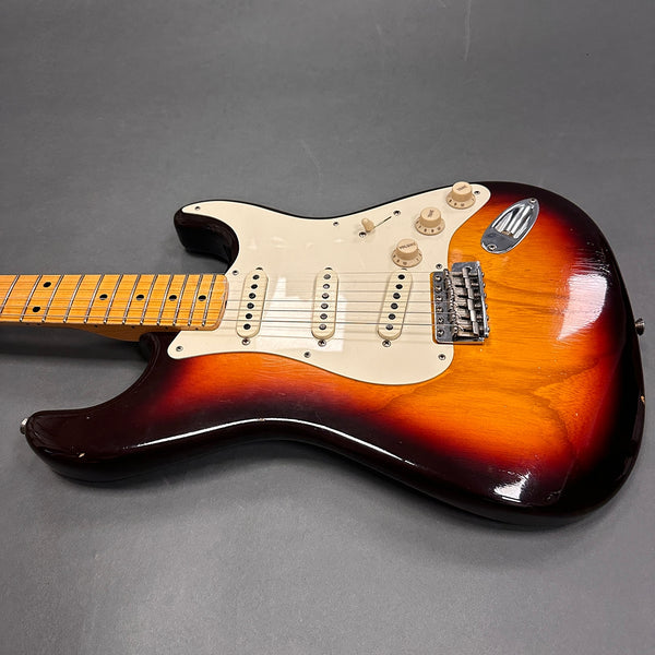 Vintage sunburst electric guitar with maple neck and three single-coil pickups on gray background