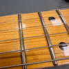 Close-up image of guitar fretboard showing metal frets, steel strings, and dot inlays on a light-colored wood fingerboard