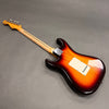Back side view of sunburst electric guitar with maple neck and tuning pegs on gray background