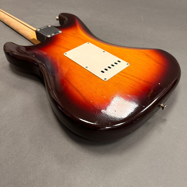 Vintage sunburst electric guitar body with cream backplate and maple neck on gray background, showing wear and finish checking