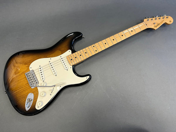 Fender Stratocaster electric guitar with sunburst finish, maple neck, and white pickguard on gray background