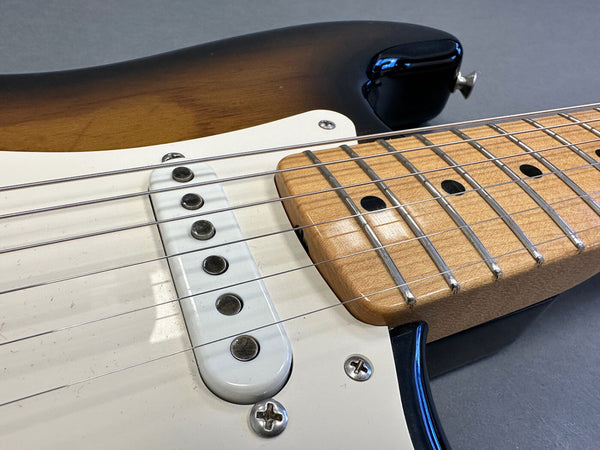 Close-up of sunburst electric guitar body, white pickguard, single-coil pickup, and maple fretboard with metal frets and black dot inlays