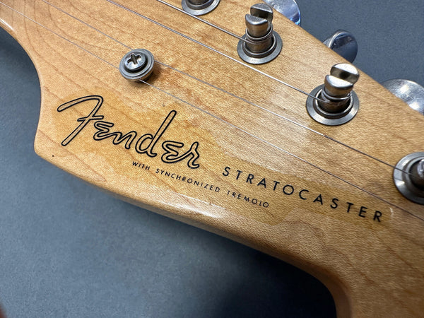 Close-up of Fender Stratocaster guitar headstock with tuning pegs and synchronized tremolo label