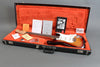 Fender Stratocaster electric guitar in sunburst finish inside black hard case with orange plush interior, including Fender manuals and accessories.