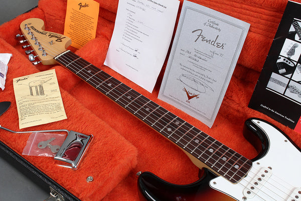 Fender Stratocaster electric guitar in black with rosewood fretboard inside orange plush-lined hard case, including Fender certificate of authenticity, tremolo springs instruction sheet, keys, and setup checklist