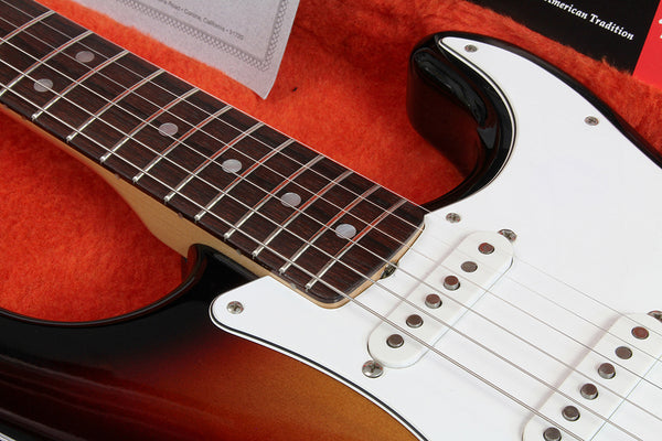 Close-up of electric guitar neck and pickups with sunburst finish inside orange plush case at Coffee House Guitars