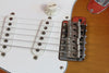 Close-up of electric guitar bridge, volume knob, and white single-coil pickups on a brown body guitar