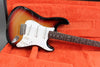 Sunburst electric guitar with white pickguard and rosewood fretboard in orange plush guitar case