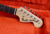 Close-up of Fender Stratocaster electric guitar headstock with tuning pegs on orange plush guitar case lining
