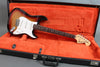 Fender Stratocaster electric guitar with sunburst finish in open black hard case with orange plush interior.